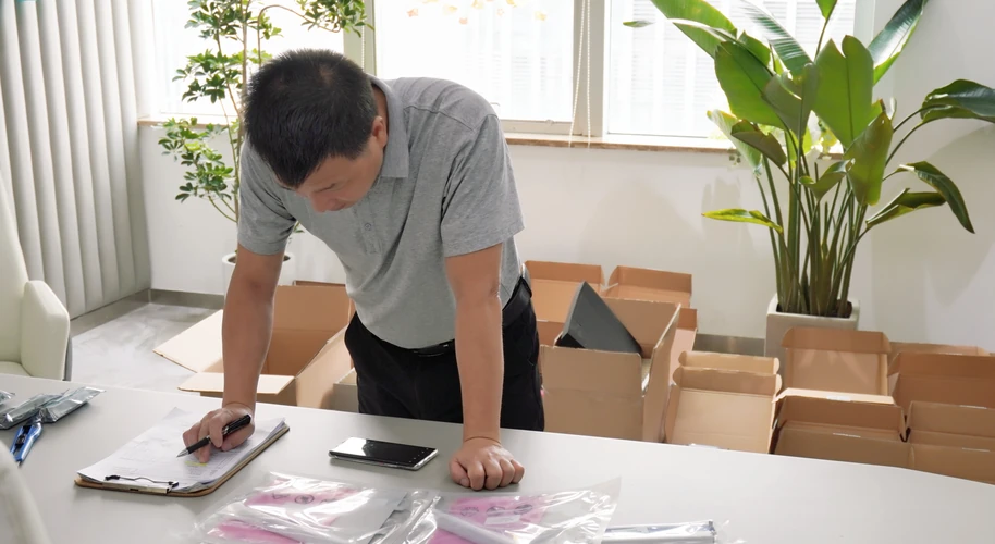 A worker checking paperwork beside individually packaged components.