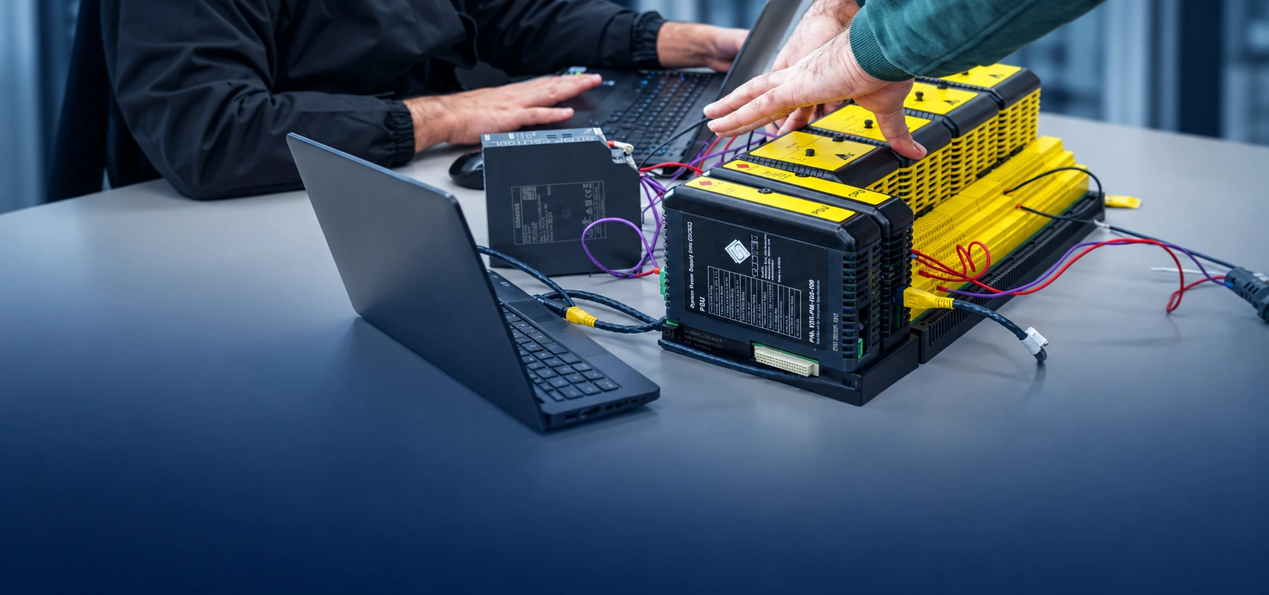 Customer and staff reviewing a PLC testing setup